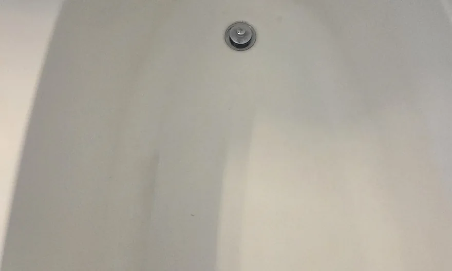The same bathtub after cleaning, with the basin and drain area visibly clear.