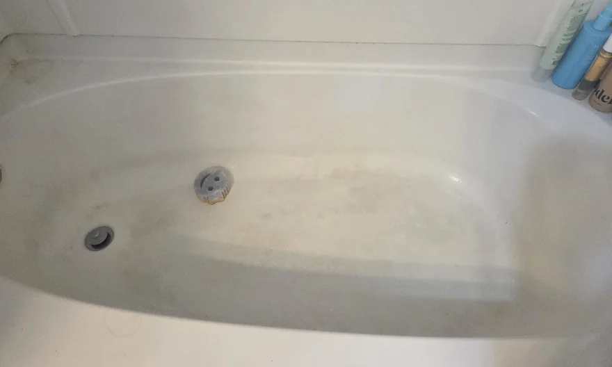 Bathtub before cleaning, with visible dull residue and a ring around the drain.