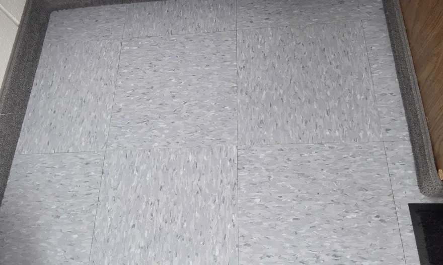 The same vinyl tile floor after cleaning, with the spill lifted and the tile uniformly clean.