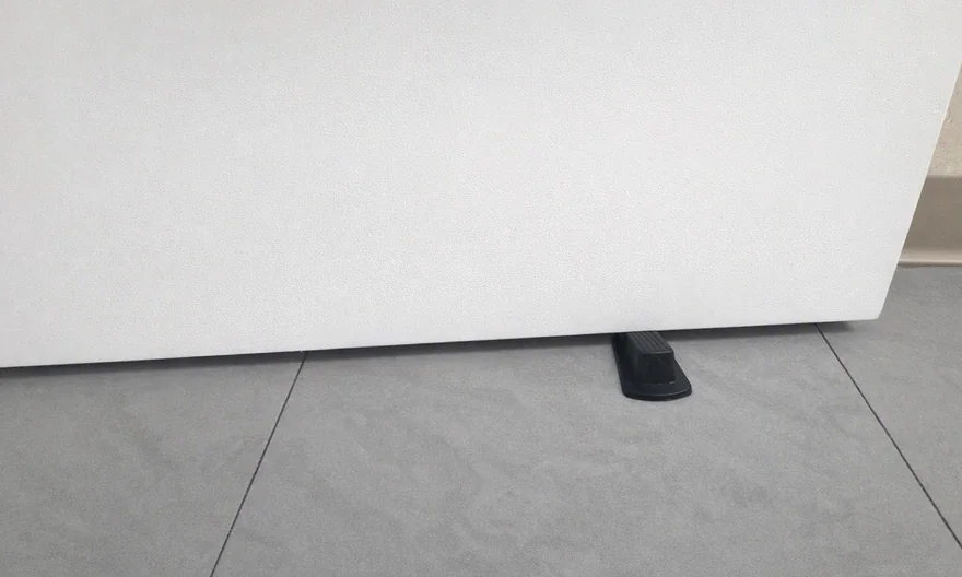 The same restroom door after cleaning, with the lower edge and surrounding floor clear of buildup.
