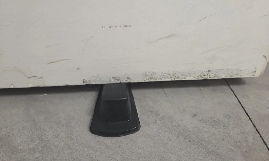 Lower restroom door before cleaning, with dark scuffs and buildup along the bottom edge.