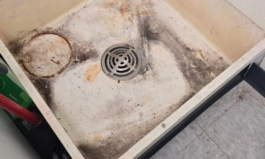 Utility sink before cleaning, with dark grime and a ring of residue around the drain.